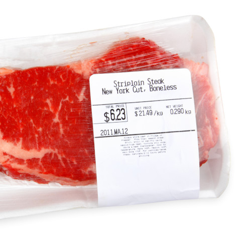 A packaged steak sits isolate on a white background.